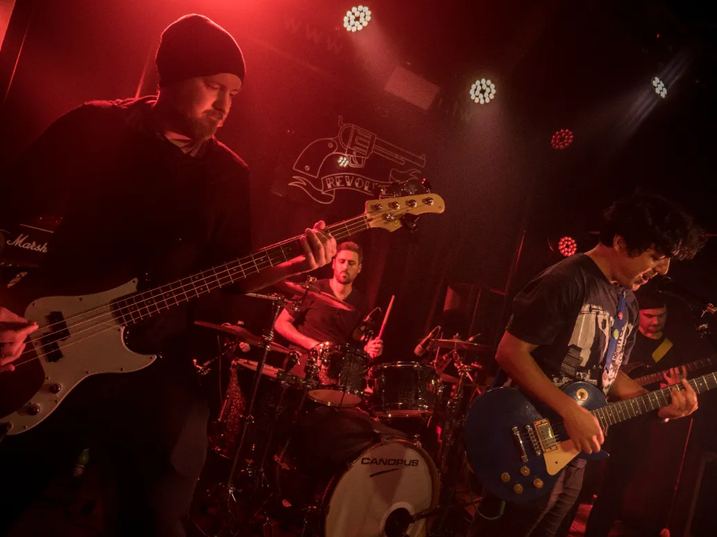 All four members of Pangolin on stage under a red light